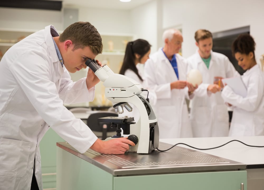 Young medical student working with microscope at the university