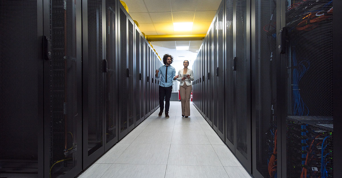 Two people walking and talking in a data center. 