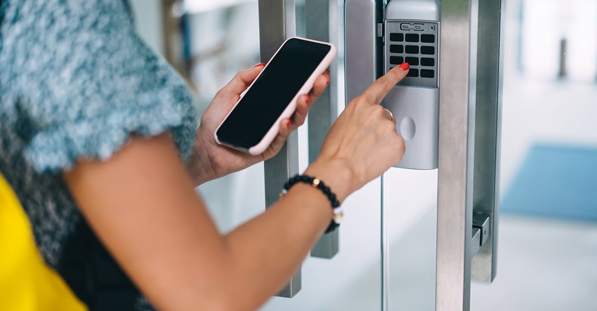 Woman using her phone and an access control system to enter through a door. 